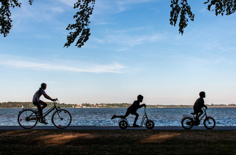 Fotografía de 3 personas paseando en bicicleta con un fondo de mar